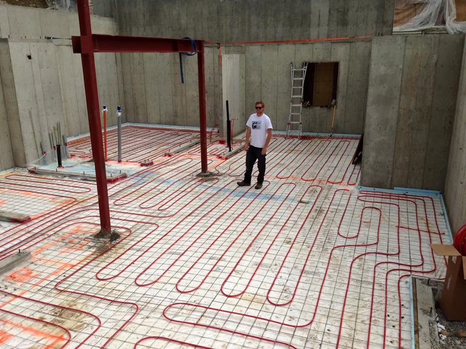 Red in-floor radiant heating tubing laid across a concrete slab