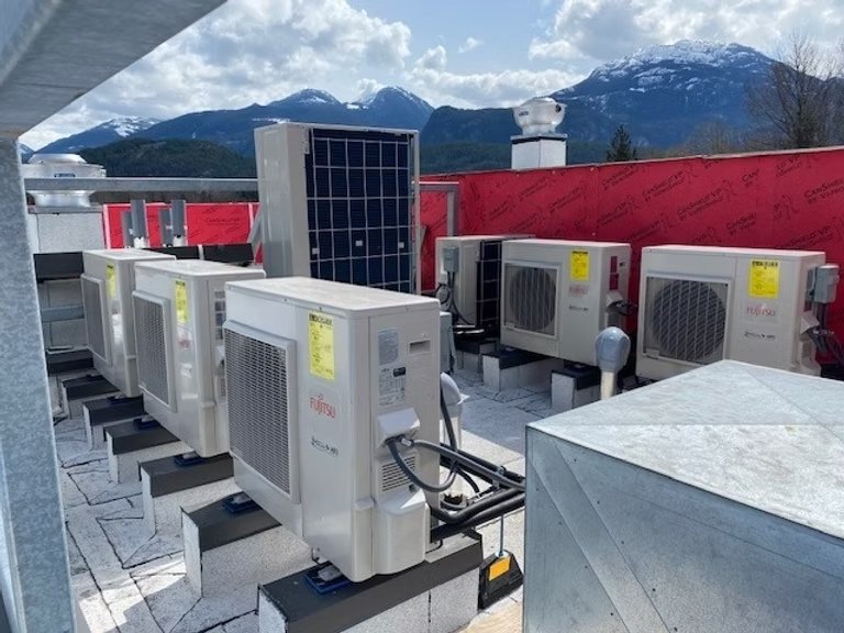 Row of Fujitsu heat pump units on a rooftop with mountains behind