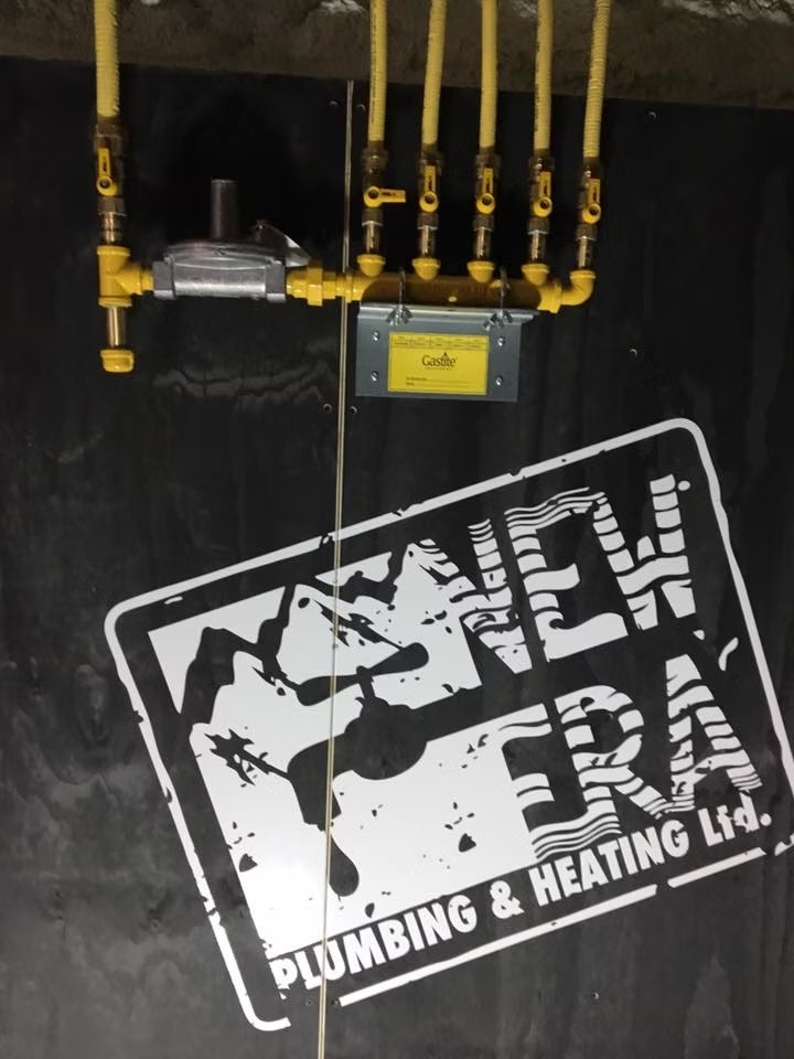 Yellow gas lines and manifold on a black wall stencilled with the New Era logo